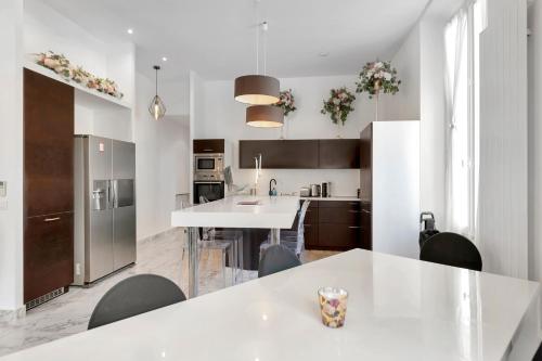 une cuisine avec des comptoirs blancs et une table et des chaises blanches dans l'établissement Le Borniol, splendid 3 bedrooms Appt, Cannes Center, à Cannes