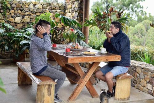 dos hombres sentados en una mesa de picnic comiendo comida en Cabaña en la Mesa de los Santos, en Piedecuesta