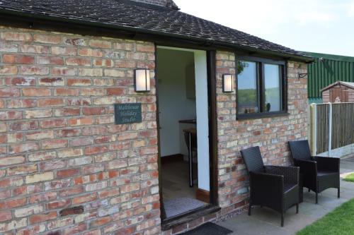 a brick building with a mirror and two chairs at Malthouse Farm Cottage Studio in Dilhorne
