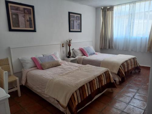 1 dormitorio con 2 camas y ventana en SOLACHE INN, en Zitácuaro