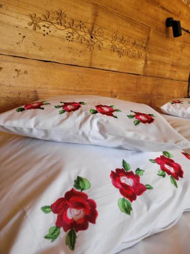 two white pillows with red flowers on them on a bed at Stary Dom z Piwnicą in Krynica Zdrój