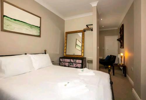 a bedroom with a white bed with a mirror and a chair at Stones Throw in Scarborough