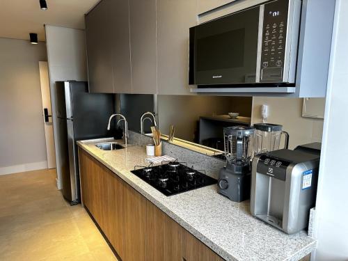 uma cozinha com um fogão e um micro-ondas em PARK SUL - Edifício Essence - 10 em Brasília