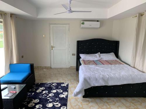 ein Schlafzimmer mit einem schwarzen Bett und einem blauen Stuhl in der Unterkunft HERITAGE LODGE & EVENT CENTER in Ada