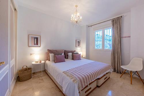 a bedroom with a bed and a window and a chandelier at La Cala golf and Sun apartment in Mijas
