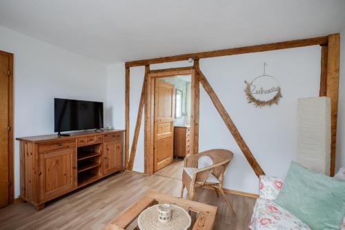 a living room with a tv and a chair at Ferienwohnung Spatzennest in Hellenhahn-Schellenberg