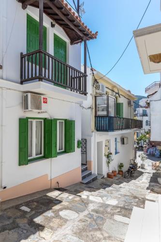 a building with green shutters and a balcony at Sofia's House - Skopelos Town in Skopelos Town