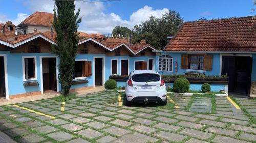 a car parked in a parking lot in front of a house at Pousada Aconchego in Monte Verde