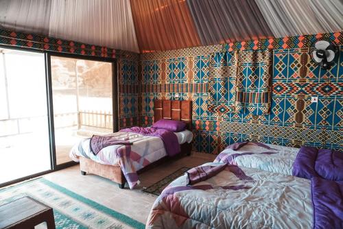 een slaapkamer met 2 bedden in een kamer met kleurrijk behang bij Solana Desert Camp & Tour in Wadi Rum