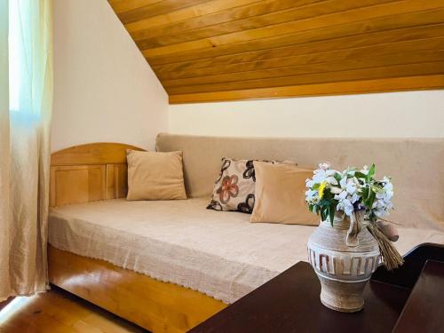 a small bed with a vase with flowers on a table at River View Tiny House with Garden in Šipovo
