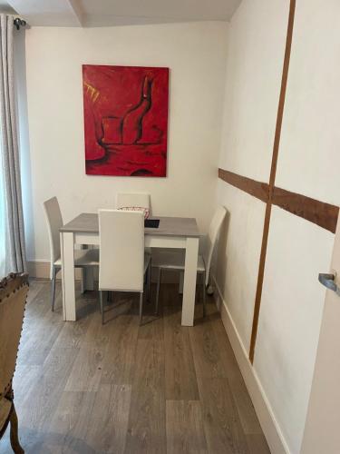 a dining room with a table and a painting on the wall at Soso house in La Ferté-sous-Jouarre