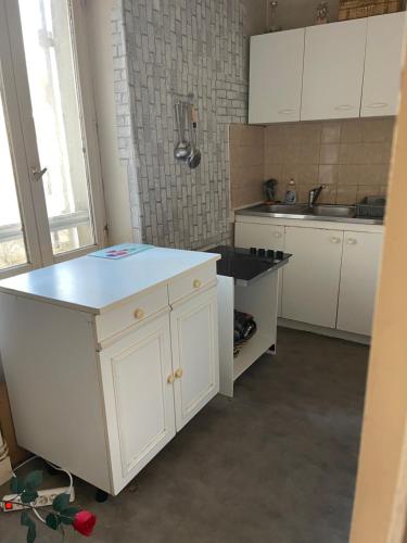 a kitchen with white cabinets and a blue counter top at Soso house in La Ferté-sous-Jouarre