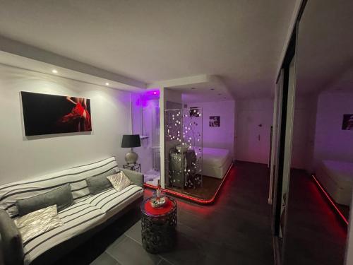 - un salon avec un canapé et un lit avec des lumières violettes dans l'établissement Studio Haut de Gamme : Sunshine, au Cap d'Agde