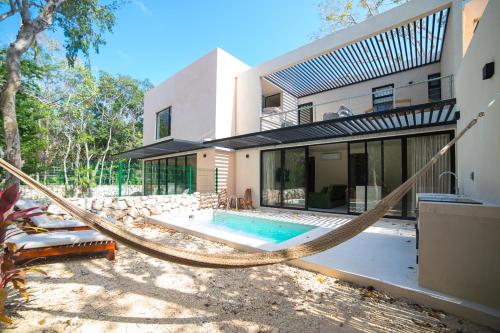 Brand NEW! Tulum Jungle Villa with private pool في تولوم: أرجوحة أمام المنزل مع مسبح