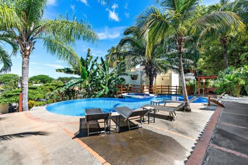 a swimming pool with chairs and palm trees at Modern Split-Level 2-Bedroom Condo with Pools, Terrace & Easy Beach Access in Coco