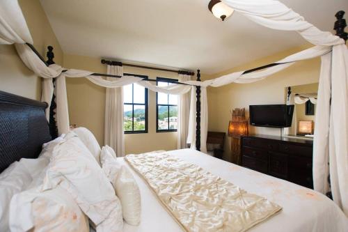 ココにあるClassy artsy ocean-view unit near pool at Pacifico in Coco sleeps 6のベッドルーム(天蓋付きベッド1台、テレビ付)