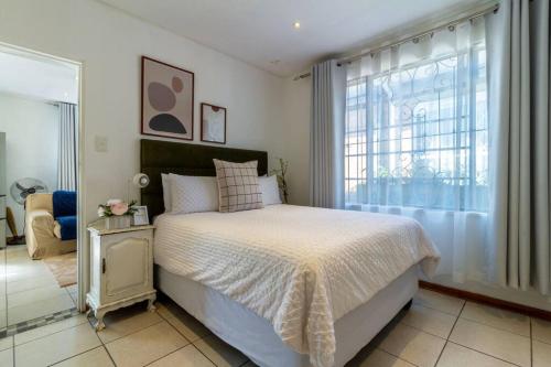 um quarto com uma cama e uma grande janela em 1 Bedroom Apartment in Houghton with Uninterrupted WiFi em Joanesburgo