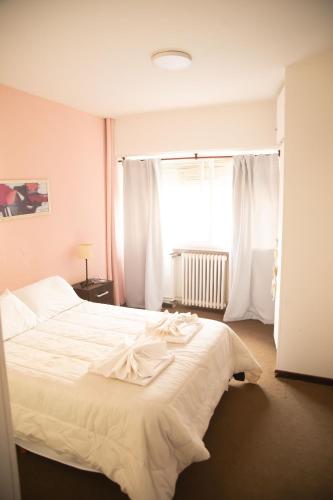 um quarto com uma grande cama branca em frente a uma janela em HOSTERIA AKINO em Esquel