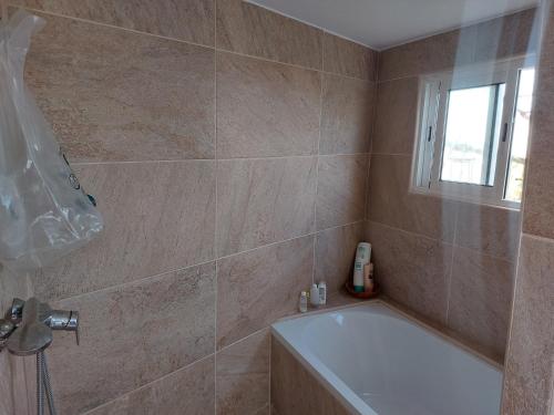 a bathroom with a bath tub and a window at Twin room in the greenhouse close to mountains and surf paradise in Tejina