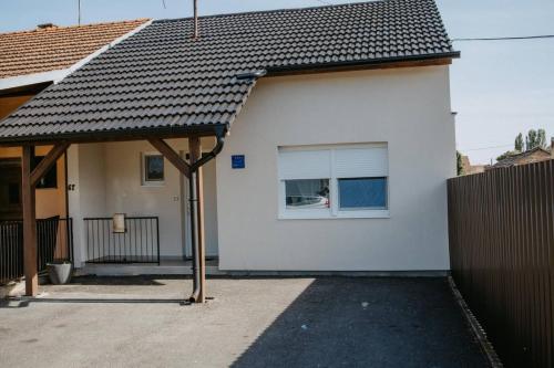 a white house with a window and a fence at Apartman Luka in Vinkovci