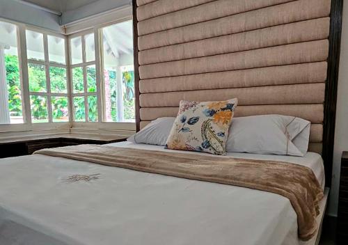 a bedroom with a bed with a headboard and windows at HOTEL SANTAFE NATURA - SANTAFE DE ANTIQUIA in Santa Fe de Antioquia