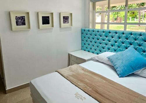 a bedroom with a blue tufted bed and a window at HOTEL SANTAFE NATURA - SANTAFE DE ANTIQUIA in Santa Fe de Antioquia