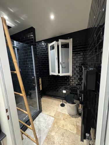 a bathroom with a shower and a black brick wall at Maisonnette calme in Mouy