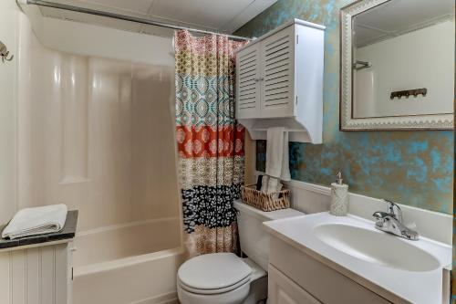 a bathroom with a toilet sink and a shower curtain at Oceanfront * Pool * Elevator * Boardwalk in Carolina Beach