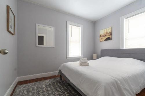 a white bedroom with a bed and two windows at Stylish 2-Story Home with Workspace in Detroit
