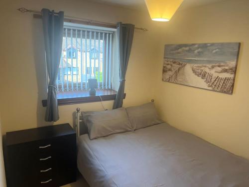 a bedroom with a bed with a dresser and a window at Sunny Cove Holiday Let in Aberdeen