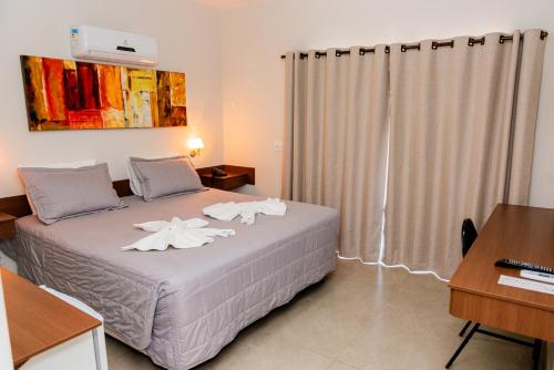 a bedroom with a bed with white flowers on it at Hotel Fernandão in Pouso Alegre