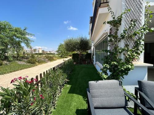 a garden with chairs and flowers next to a building at Stunning groundfloor apartment - MO2802LT in Los Tomases