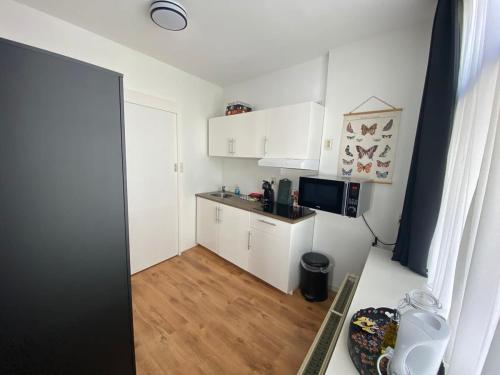 una pequeña cocina con armarios blancos y suelo de madera. en Hello Zeeland - Appartement Molstraat 23, en Middelburg