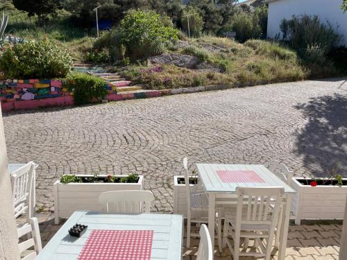 a patio with white tables and chairs on a brick road at Ada Olympos Otel in Bozcaada