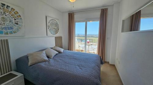 una camera con un letto blu e una finestra di Homely apartment on la Torre Golf Resort ER2321LT a Torre-Pacheco