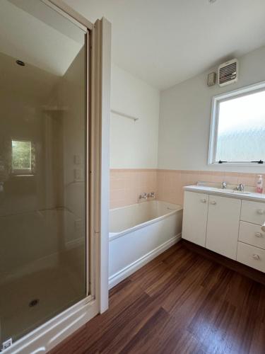 een badkamer met een douche, een bad en een wastafel bij 15 Caverhill Close in Hanmer Springs