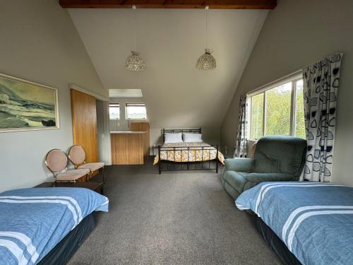 een slaapkamer met 2 bedden en een bank en een stoel bij 15 Caverhill Close in Hanmer Springs