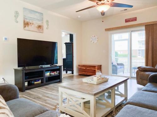 a living room with a tv and a coffee table at Lakefront at Barefoot Resort w Massive Waterfront Pool Close to Beach in North Myrtle Beach