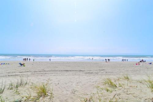 a group of people on a beach near the ocean at Ocean Blvd Paradise Steps to Beach w Pool and Grill in Myrtle Beach