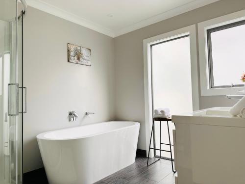 a white bathroom with a tub and a sink at Summer Holiday 4 bedrooms house in Hamilton with pool and spa in Hamilton
