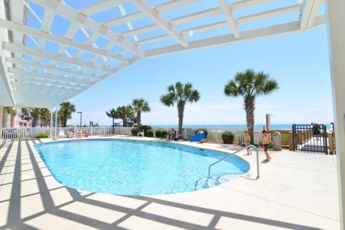a swimming pool with a pergola and a woman playing in the water at Penthouse Stunning Ocean Views Lazy River Indoor Pool in Myrtle Beach
