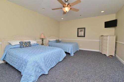 a bedroom with two beds and a ceiling fan at Tropical Cherry Grove Ocean View Beach House w Pool in Myrtle Beach