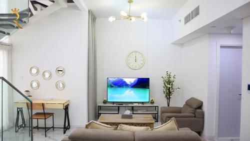 a living room with a couch and a tv on a wall at 2BR Stylish Duplex - Premium Oasis Retreat in Abu Dhabi