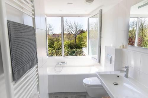 uma casa de banho branca com uma banheira, um WC e uma janela. em Hello Zeeland - Villa Jhr de Casembrootplein 23 em Domburg