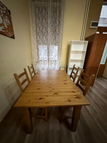 a wooden table in a room with chairs and a window at KFlat Stay in Budapest