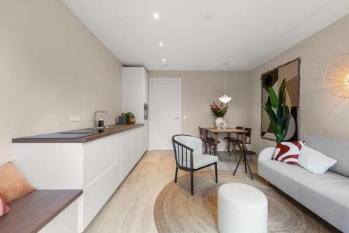 eine Küche und ein Wohnzimmer mit einem Sofa und einem Tisch in der Unterkunft Hello Zeeland - Appartement Duinenburg 10- 3 in Domburg