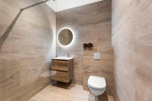 uma casa de banho com um WC, um lavatório e um espelho. em Hello Zeeland - Appartement Duinenburg 10- 3 em Domburg