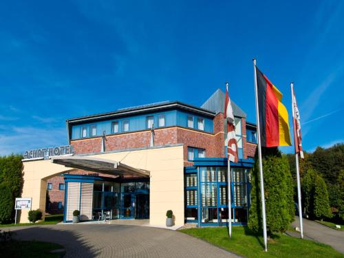 un bâtiment avec deux drapeaux devant lui dans l'établissement ACHAT Hotel Bochum Dortmund, à Bochum