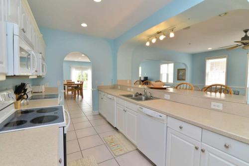 a large kitchen with white cabinets and blue walls at Tropical Rays Huge Cherry Grove House w Pool in Myrtle Beach