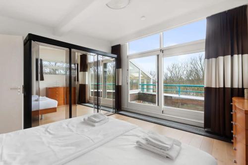 a bedroom with a white bed and large windows at Hello Zeeland - Appartement Loverendale 38 in Domburg